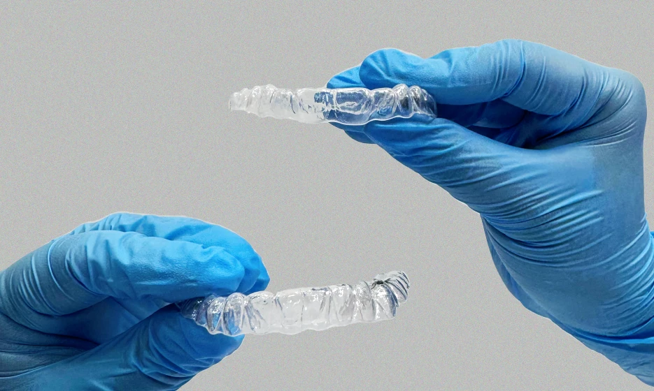 Gloved hands holding ClearPath clear aligners
