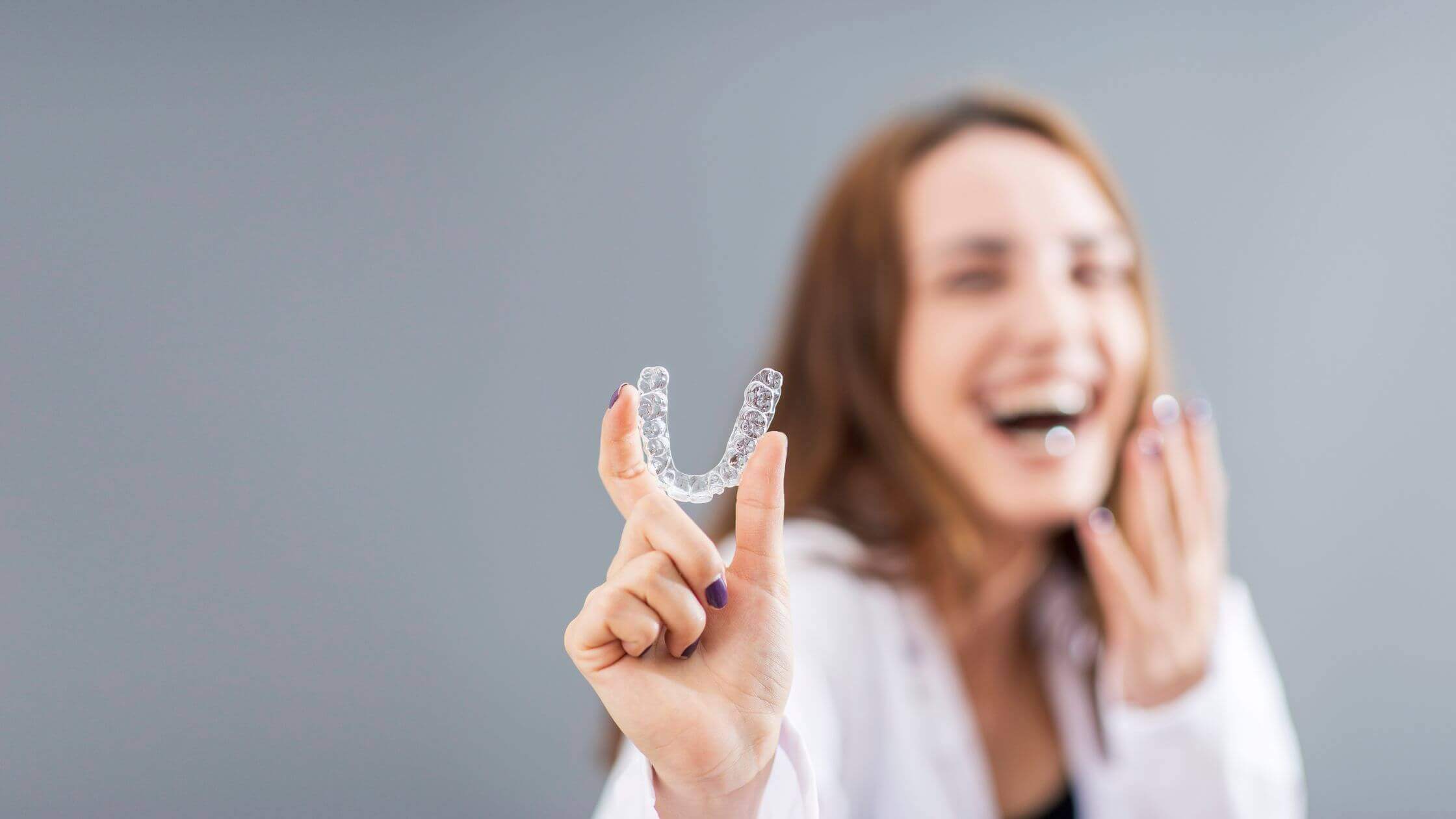 A woman holding clear aligners