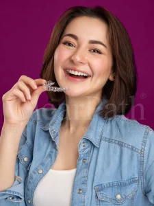 Pakistani actress Hania Amir posing with a tray of clear aligners. A complementary still for our aligners vs braces blog post.